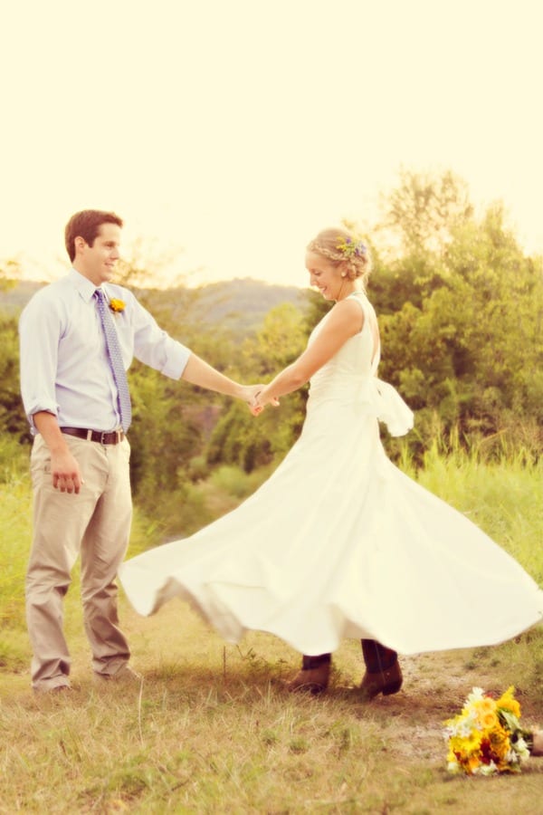 Bride twirling in white satin A-line gown with V-neckline and open back in rustic outdoor Nashville setting