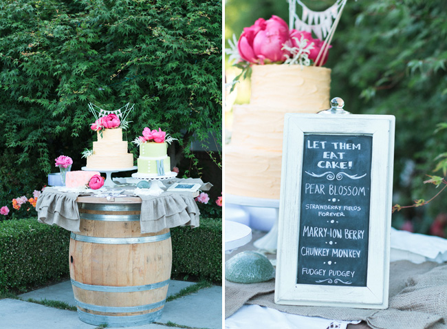 three cakes with coral peonies on top, sitting on a wine barrel table
