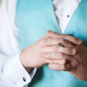 groom in tiffany blue vest holding rings