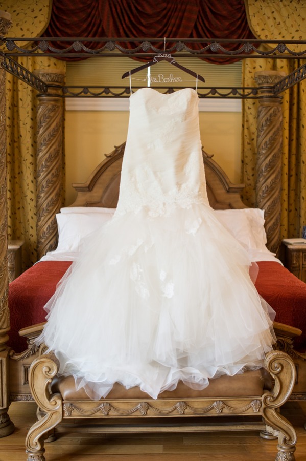 Mermaid wedding dress with sweetheart neckline and ruffled tulle skirt displayed on ornate canopy bed