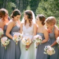10 bride wearing illusion neckline wedding gown with bridesmaids wearing grey dresses