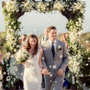20 bride and groom walking down aisle while guest throw rose petals in the air