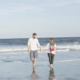 Couple-walking-on-beach-away-from-the-shoreline