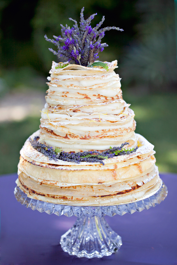Tall stack of crepes decorated with lavender on a faceted clear glass pedestal stand