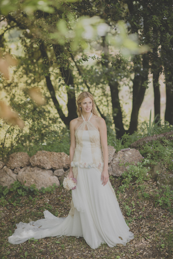 Bride in ethereal halter neck gown with flowing tulle skirt standing in Spanish woodland with soft natural light
