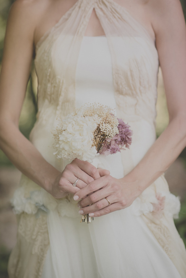 Bride holding small delicate bouquet of white and dried mauve hydrangeas