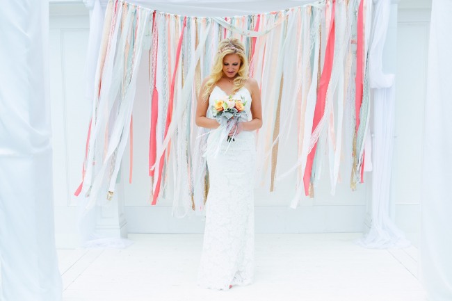 bride standing in front of ribbon and lace ceremony backdrop