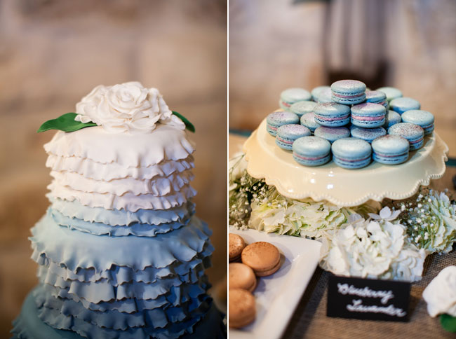 A tiered cake featuring white and blue ruffled icing with a white flower on top, next to a stand of blue macarons arranged in a circle, showcases elegant wedding cake styles.