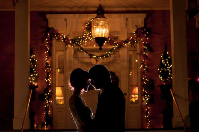 Bride and groom head to head with Christmas light in the back ground 