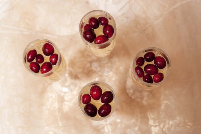 Champagne cocktail with red cranberries floating at the top 