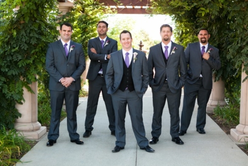 groom-and-groomsmen-stand-under-trelice-dressed-in-purple-neckties