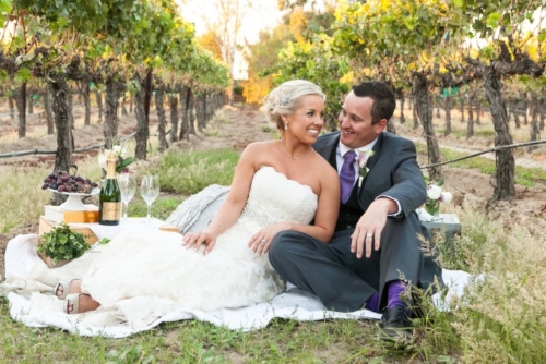 smiling newlyweds picnic in Lorimar Winery vineyard