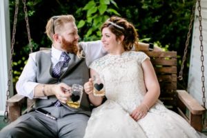 newlyweds sit on swinging porch bench