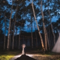 backlit newlyweds next to teepee at night