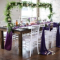 styled table with green arbor and purple fabric tied to chairs