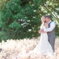 newlyweds in tall grass as sun sets
