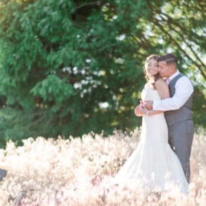 newlyweds in tall grass as sun sets