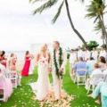 newlyweds walk on grass aisle in Maui