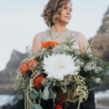 bride holds large bouquet on beach