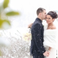 groom with bride in white shawl as snow falls