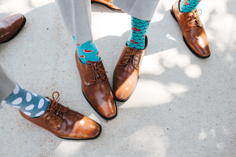 Groomsmen in grey suits and tan dress shoes wearing teal socks printed with watermelon slices and small fish