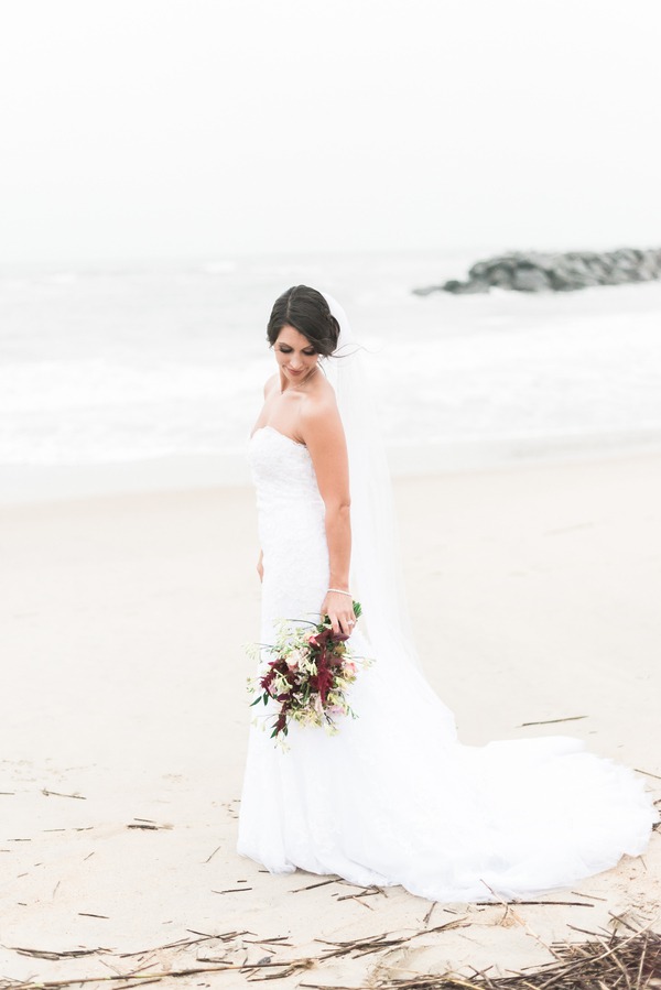 Bride with cathedral veil catching wind on Virginia beach