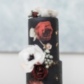 black wedding cake with white and red flowers