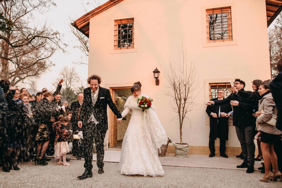 Bride in white lace A-line gown with long sleeves and illusion high neckline leaving ceremony with confetti being thrown