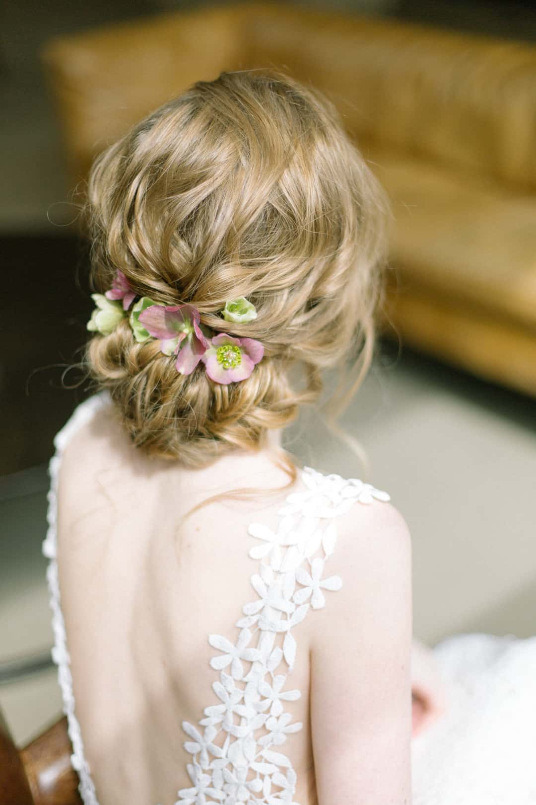 Blonde hair in a loose romantic updo with pink and green flowers tucked in