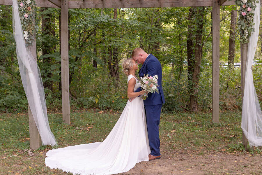 newlyweds-initmate-posed-portrait-under-wooden-awning-barn-in-zionsville