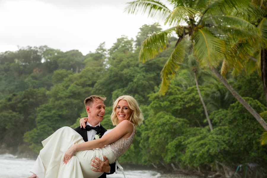 Groom carries bride on beach at Villa Punto de Vista Costa Rica