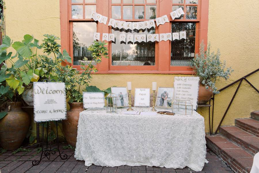 White table with white rosette tablecloth, card box, and gold candles outdoors