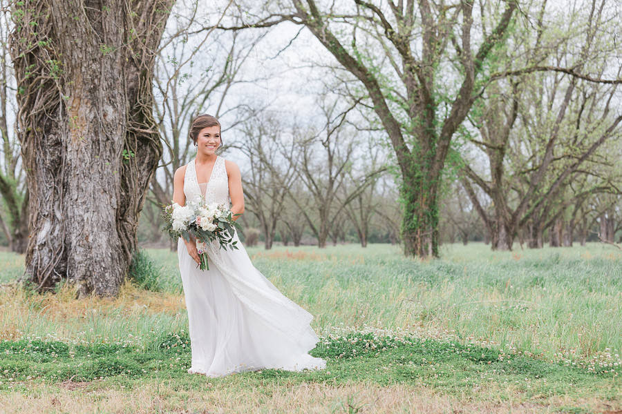 Bride portrait in flowy gown with pecan orchard backdrop