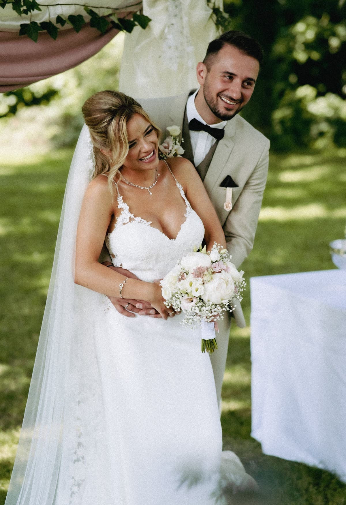 A-Groom-with-a-Bride-in-a-White-Wedding-Dress-Holding-a-Bouquet-of-Flowers.jpg