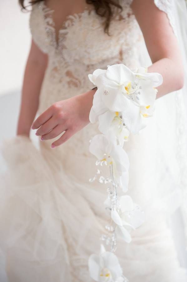 Bride in champagne lace gown holding delicate cascading white phalaenopsis orchid bouquet with crystal bead accents