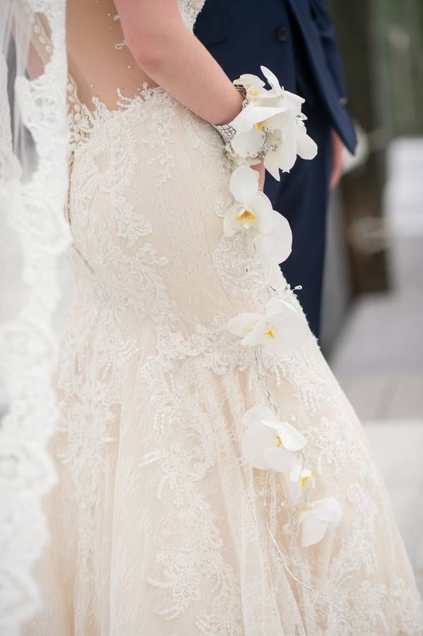Bride and groom portrait showing minimalist cascading white phalaenopsis orchid bouquet with crystal details against champagne lace gown