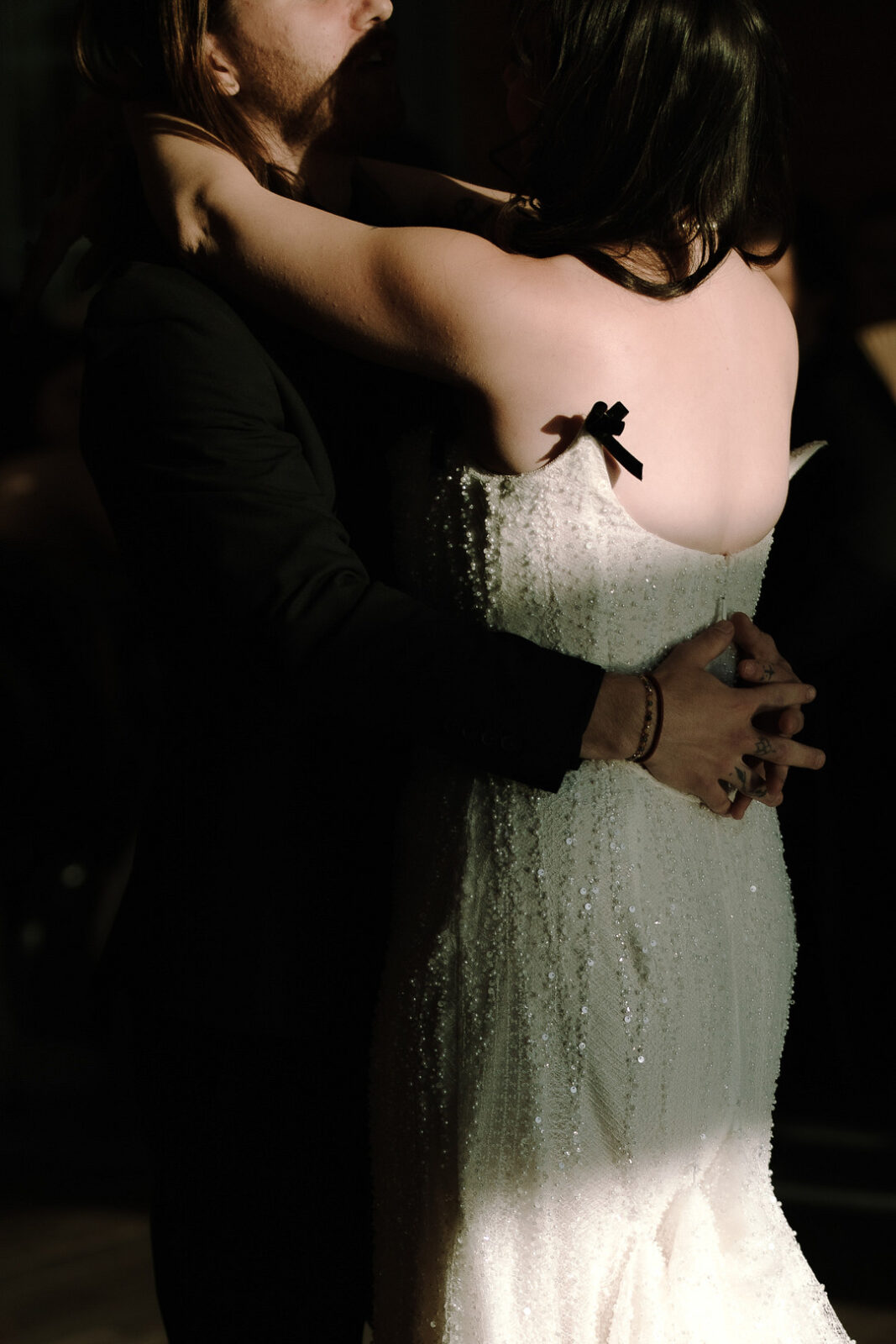 A couple dances closely at a Stone Valley Meadows celebration, with the woman's arms around the man's neck and his hands on her waist. She is wearing a sequined white dress, perfect for a romantic Spring Woodland Wedding.