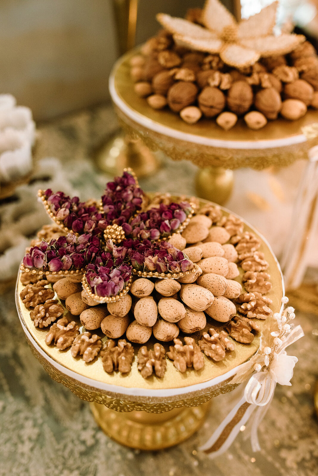 Two ornate golden trays display arrangements of walnuts, almonds, and dried flowers with decorative ribbons on the stands—perfect for a Spring Woodland Wedding at Stone Valley Meadows.