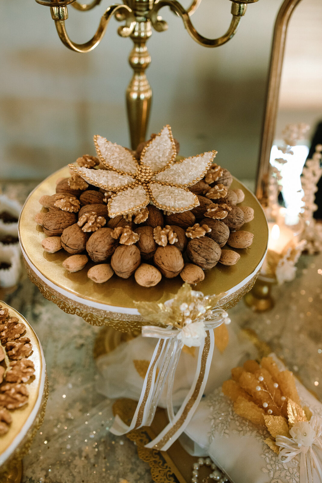 A decorative gold tray holds whole walnuts and hazelnuts, topped with a beaded flower—perfect for a Spring woodland wedding at Stone Valley Meadows, set on an ornate table.