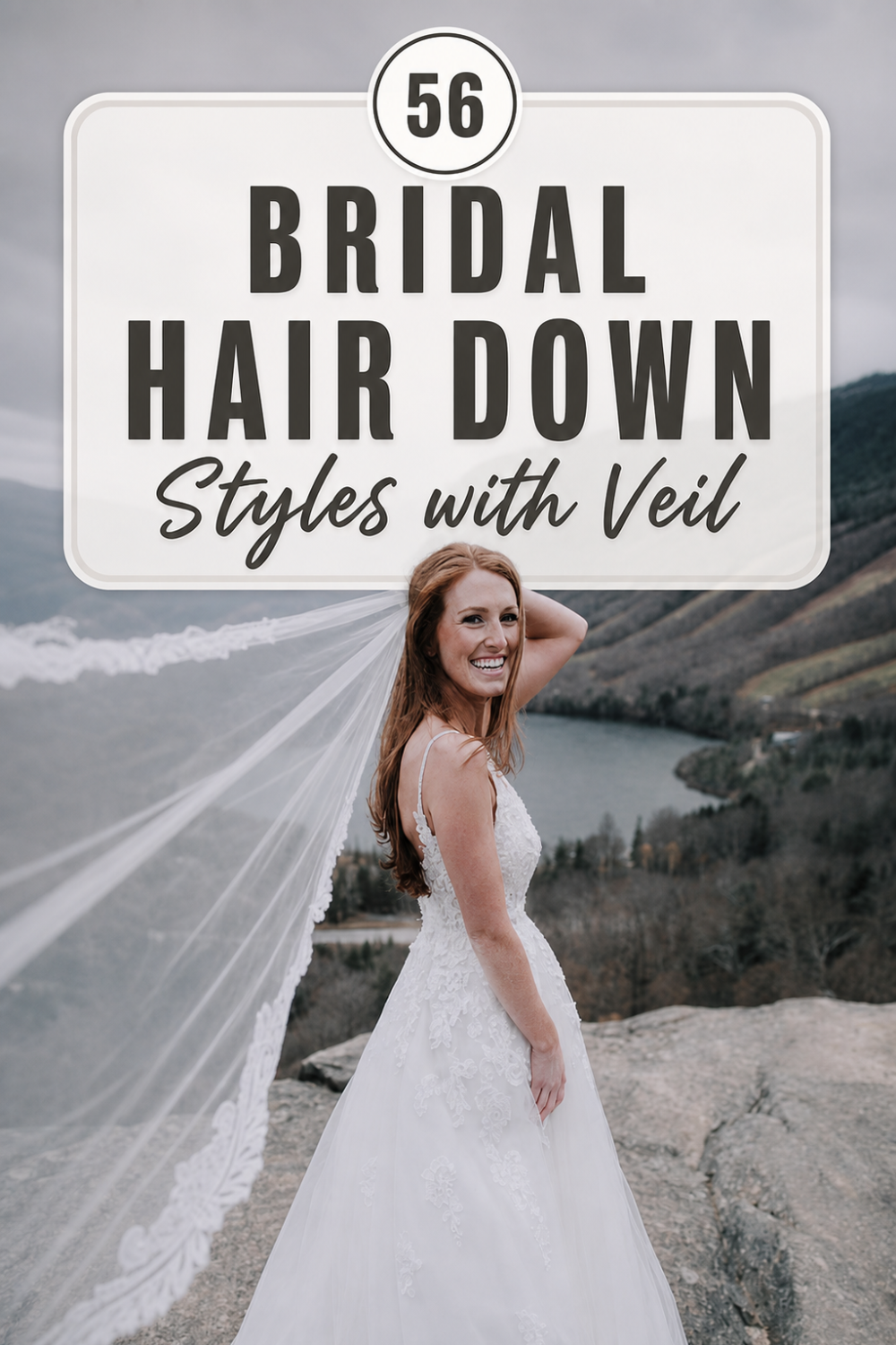 A bride with long bridal hair worn down and a veil stands outdoors on a rocky overlook, wearing a white lace wedding dress with a scenic view in the background.