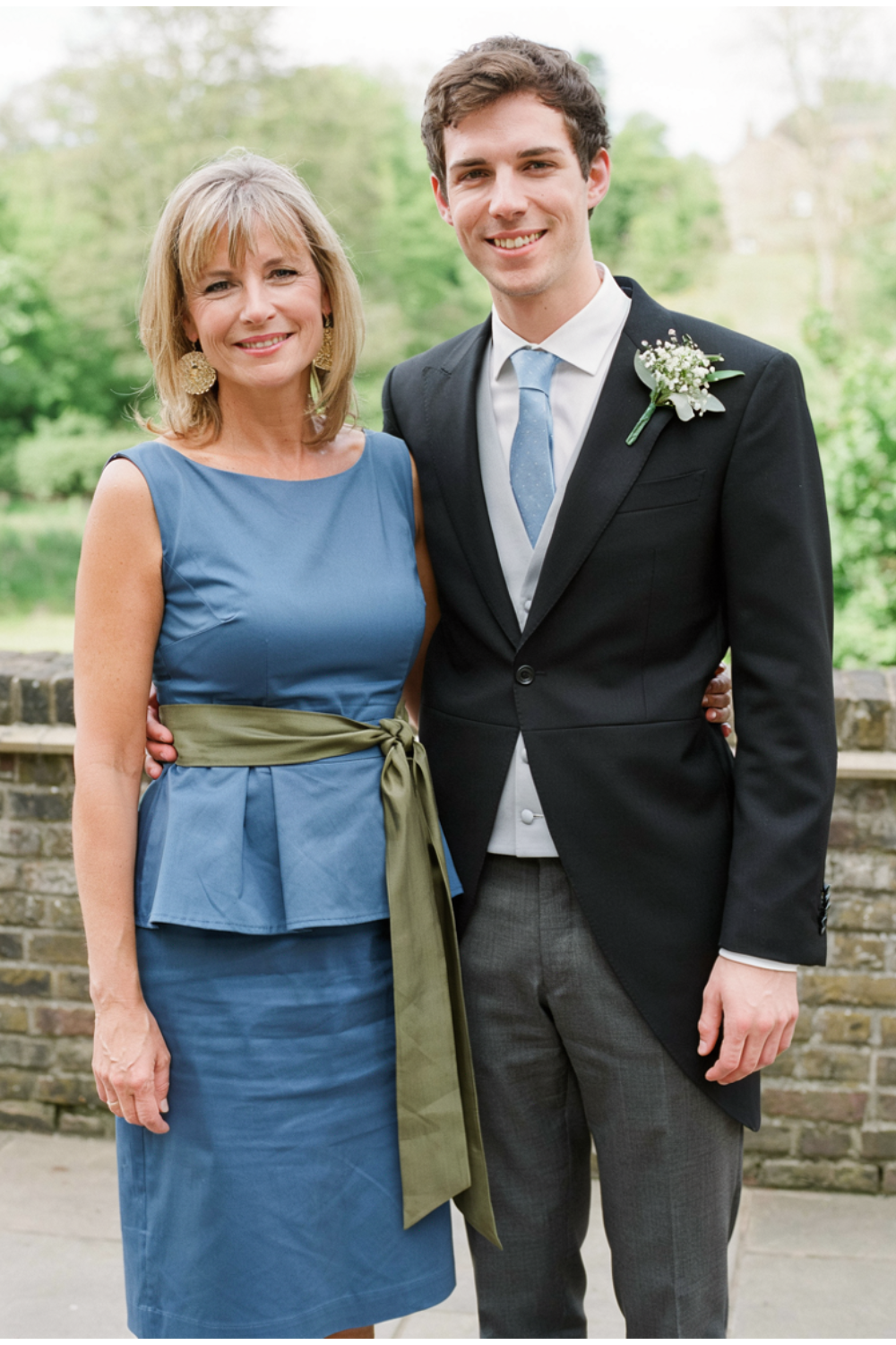 Blonde shoulder-length blowout with soft bangs and flicked ends, worn with a blue peplum dress