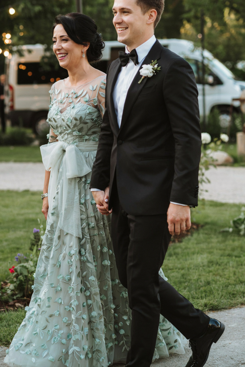 Dark hair in a low updo with a side-swept front, worn with a sage green floral appliqué gown