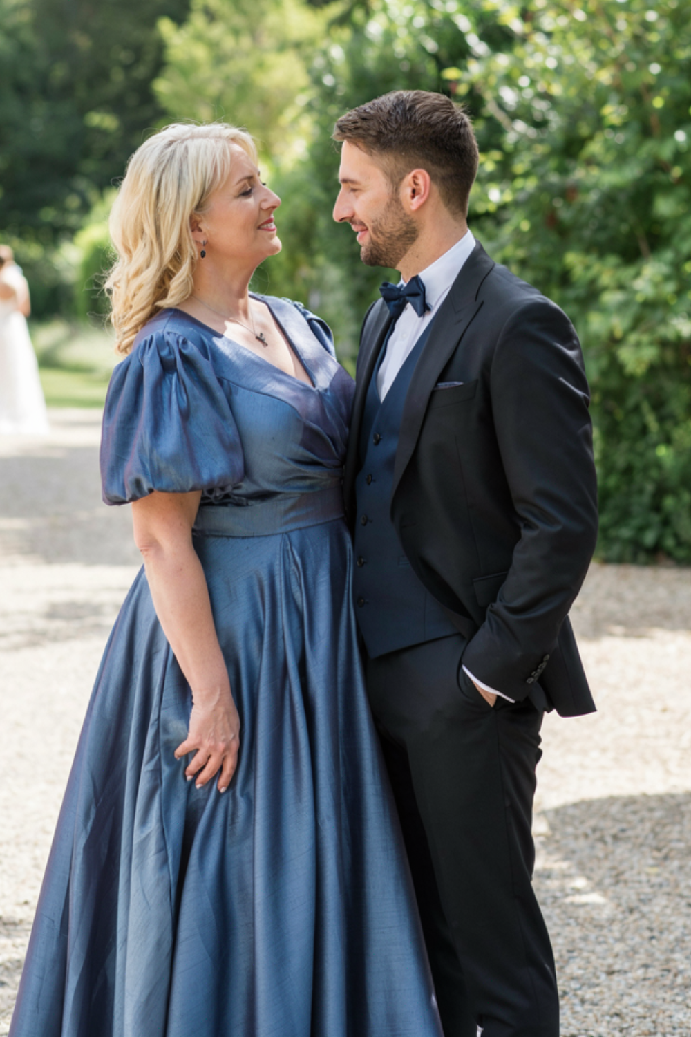 Blonde shoulder-length waves swept to one side with volume at the crown, worn with a blue taffeta gown