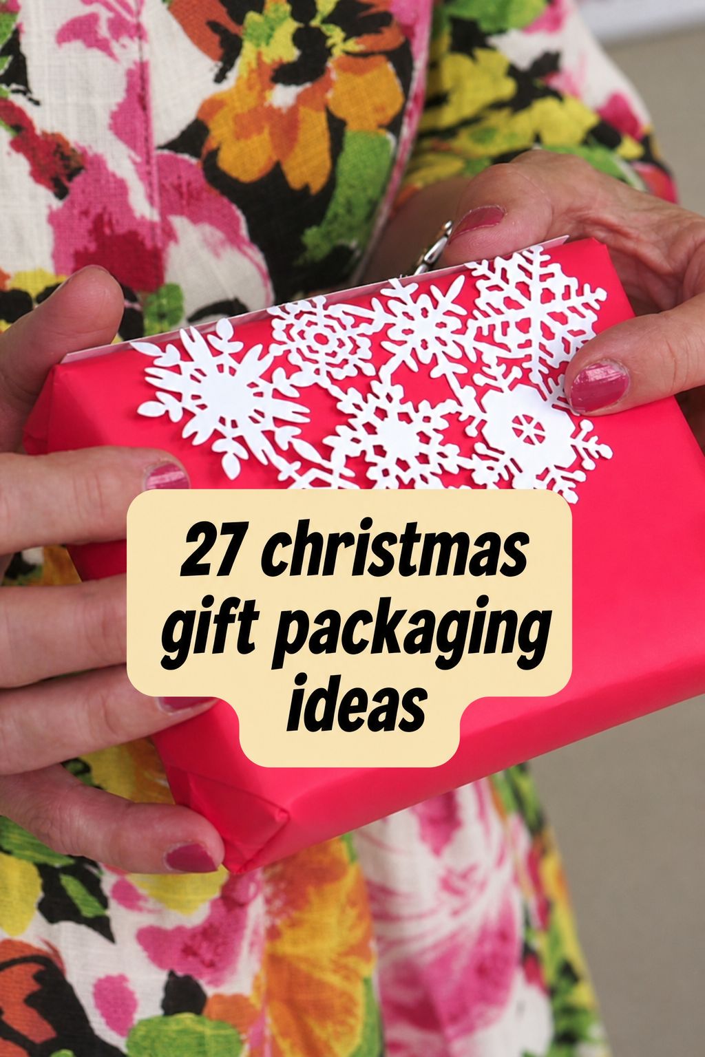 Person holding a red gift wrapped with white snowflake decorations, text overlay reads “27 Christmas wrapping ideas.” Discover festive inspiration and step-by-step videos to elevate your Christmas wrapping this holiday season.