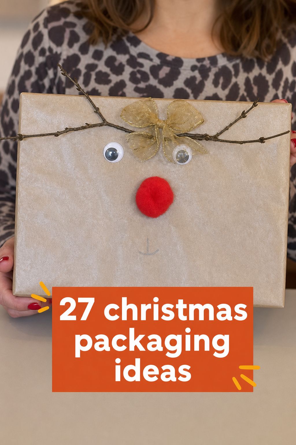 Person holding a gift wrapped to look like a reindeer with googly eyes, a red nose, and a gold bow, with text overlay: “27 Christmas Wrapping Ideas.”.