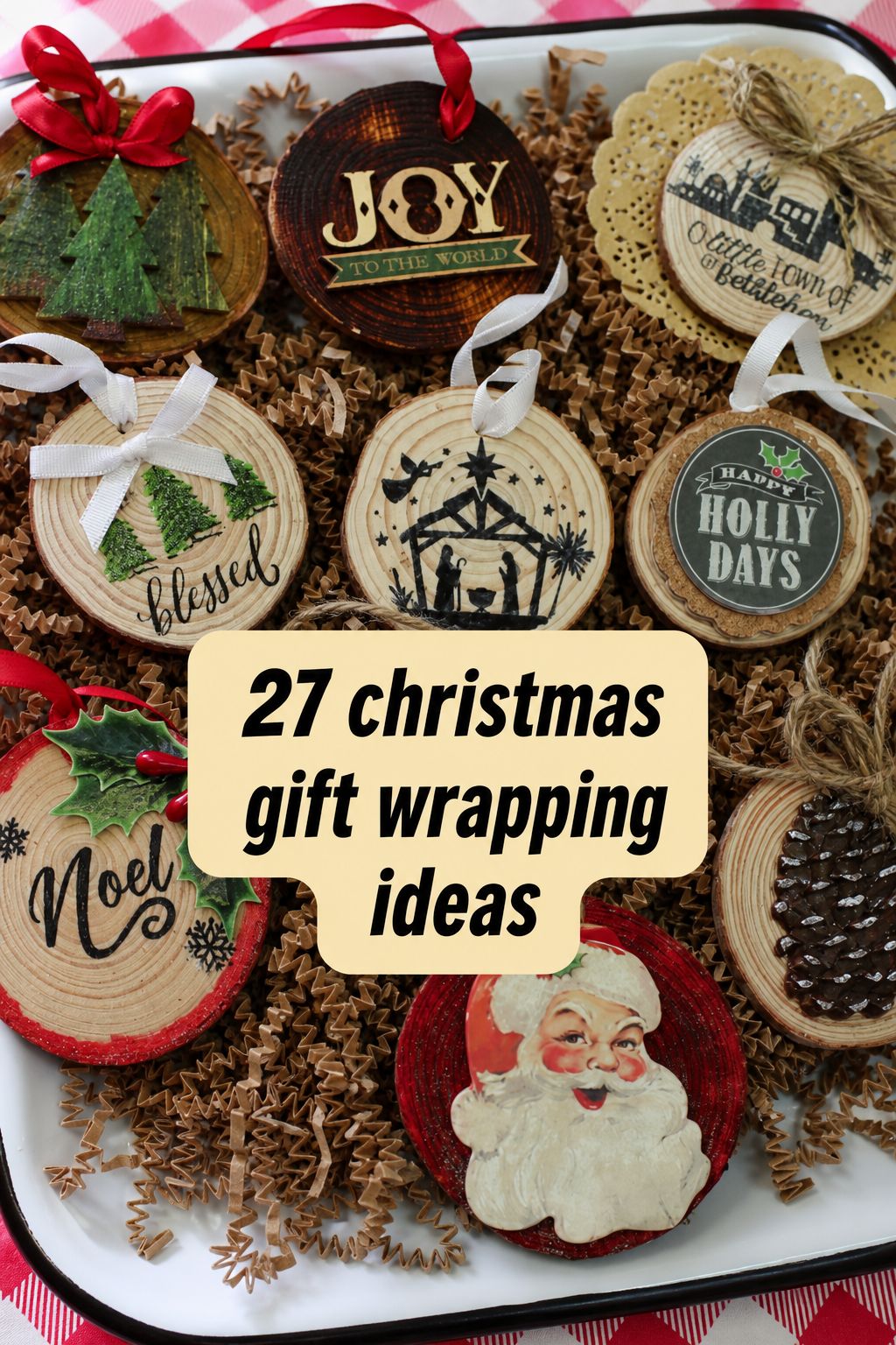 Wooden Christmas ornaments with holiday designs and text are displayed on shredded brown paper. The center text reads, “27 Christmas Wrapping Ideas,” perfect for inspiring your own festive creations. Discover step-by-step videos to elevate your Christmas wrapping this season.