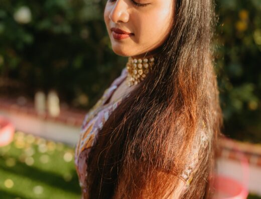 Woman with her eyes closed, wearing traditional South Asian attire and a maang tikka forehead ornament.